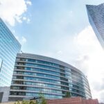 Urban cityscape with modern skyscrapers reflecting sunlight against a blue sky.